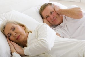 Woman snoring and man covering ears